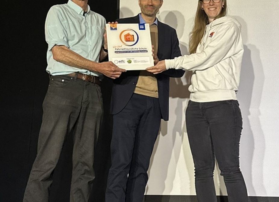 Übergabe Plakette "Fahrradfreundliche Schule" Nora Müller (links) vom ADFC SH übergibt die Plakette "Fahrradfreundliche Schule" an Mathias Kadow-Leder (Schulleiter Holstenschule) und Christian Wagner (Fahrradbeauftrager Holstenschule Neumünster)